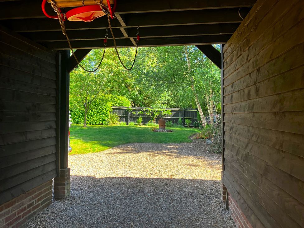A view of a garden with trees and gravel from a structure at The Hayloft - Beautiful Barn Stay in Charing