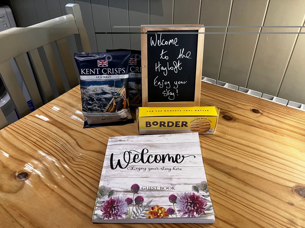 A dining room table with snacks and a welcome sign at The Hayloft - Beautiful Barn Stay in Charing