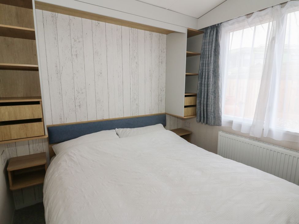 A bedroom with a bed and shelves at Hafan Y Mor in Aberporth