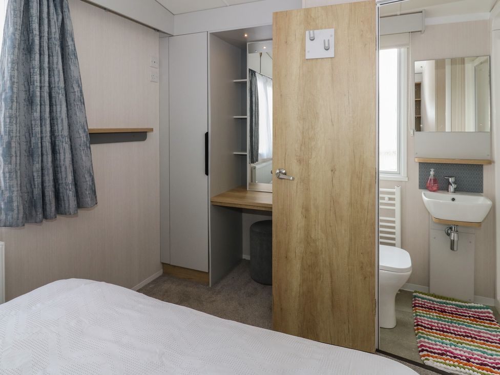 A bedroom with a bed and a bathroom area at Hafan Y Mor in Aberporth