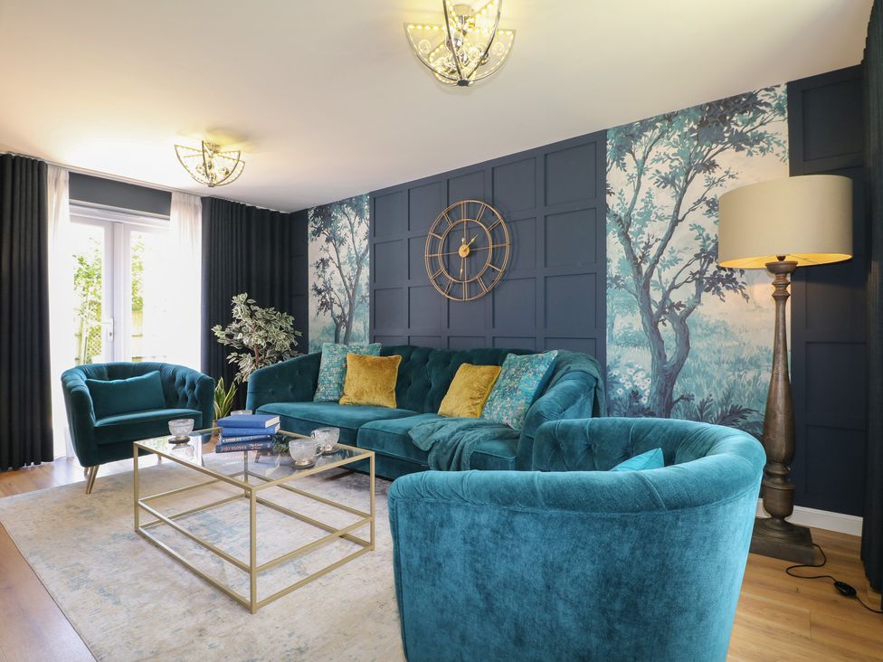 A living room with a blue sofa and armchairs at 7 Yarnfield Parkway 