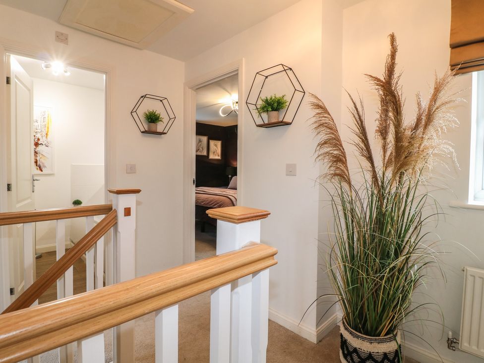 A hallway with a staircase and decorative plants at 7 Yarnfield Parkway