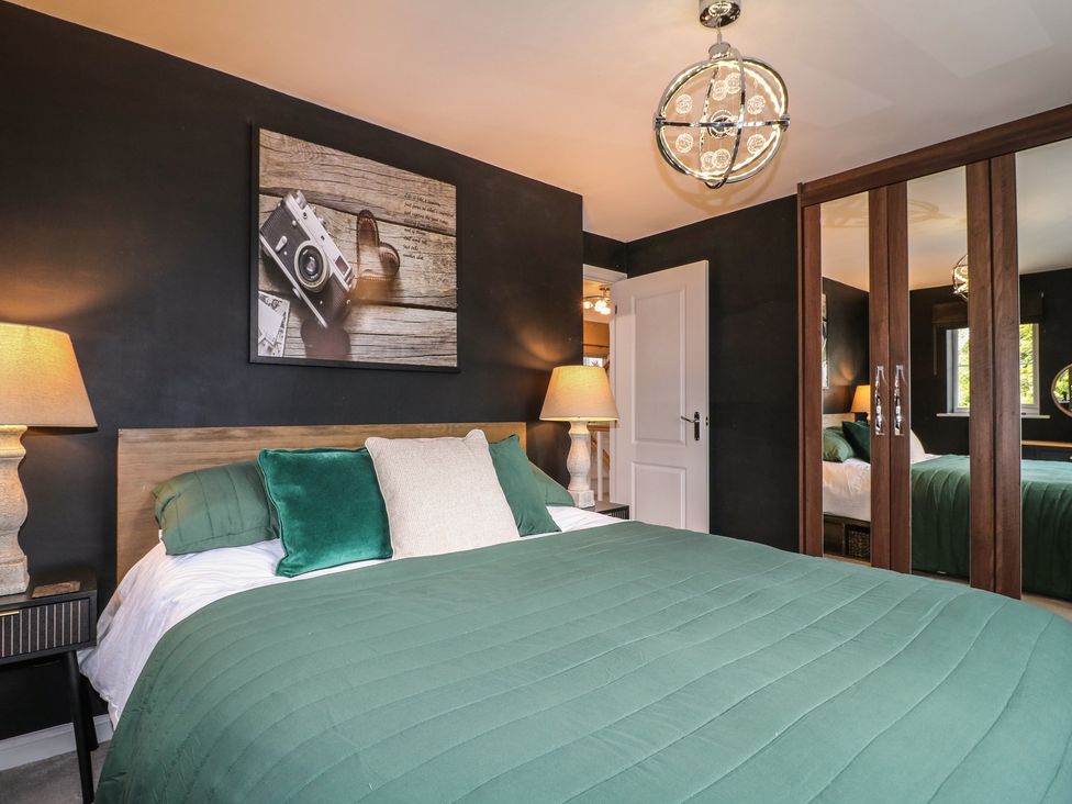 A bedroom with a green bedspread and lamps at 7 Yarnfield Parkway