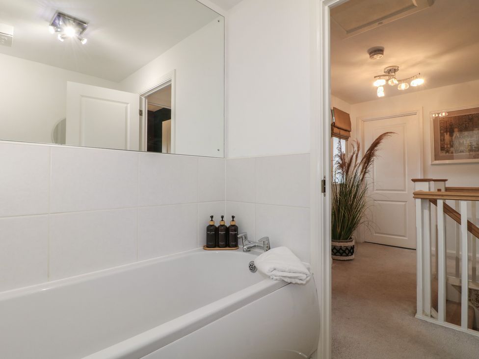 A bathroom with a bathtub and mirror at 7 Yarnfield Parkway