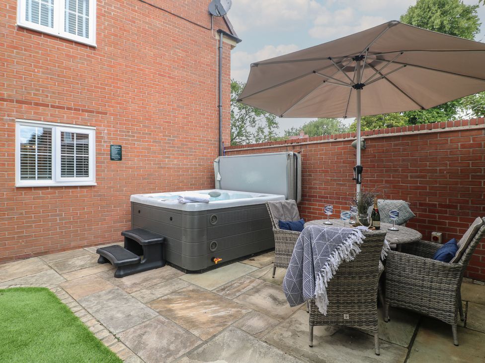 An outdoor area with a hot tub, table and chairs at 7 Yarnfield Parkway