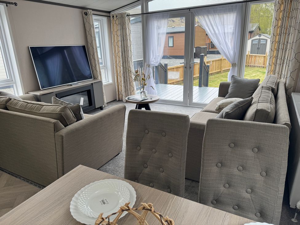 A living room with a sofa, television, and table at Lime Tree Lodge