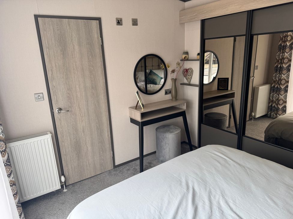 A bedroom with a desk and mirror at Lime Tree Lodge