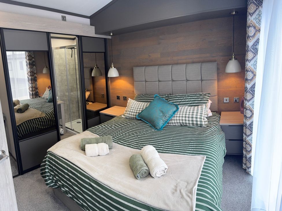 A bedroom with a bed and wardrobe at Lime Tree Lodge St Fillans