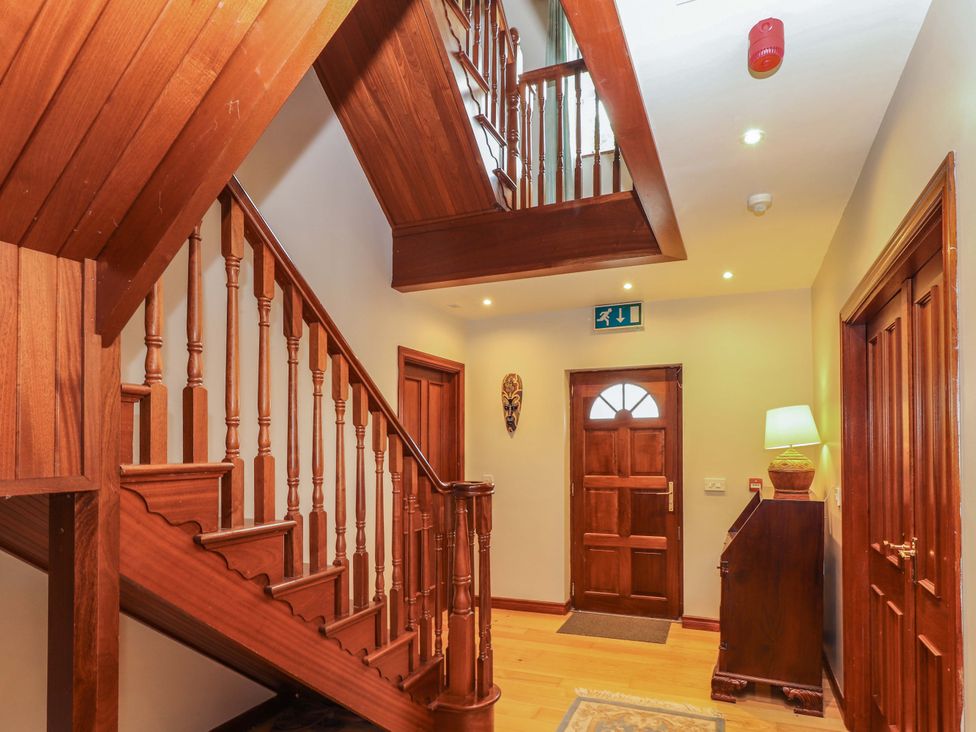 A hallway with a staircase and wooden door at Ash House in Ballyvaughan