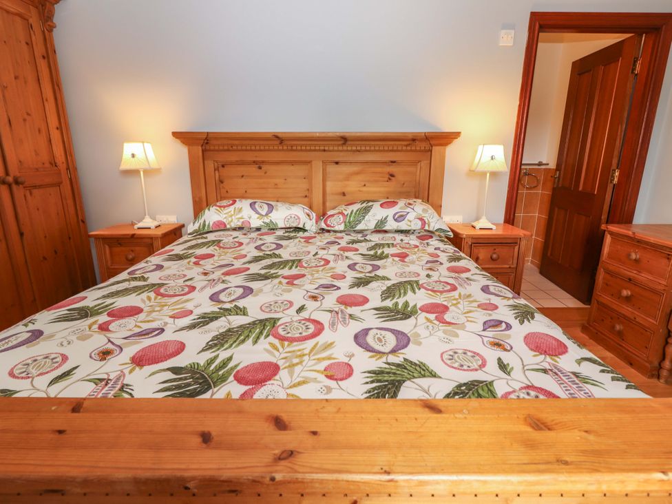 A bedroom with a bed and wooden furniture at Ash House in Ballyvaughan