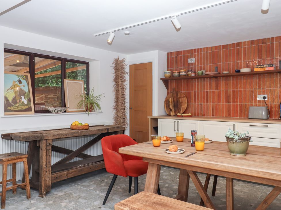 A kitchen with a wooden table and orange juice at Tigley Meadow Coach House in Totnes