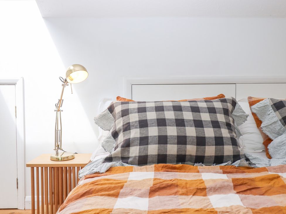 A bedroom featuring a bed with pillows and a lamp at Tigley Meadow Coach House in Totnes