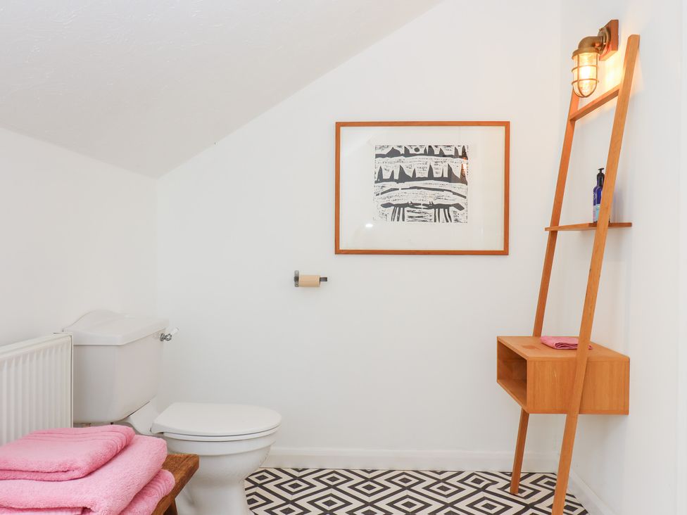 A bathroom with a toilet and shelf in Tigley Meadow Coach House in Totnes
