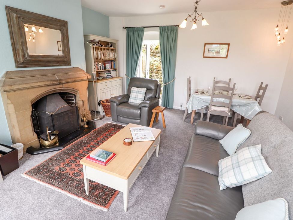 A living room with a fireplace and dining area at School Cottage in Windermere