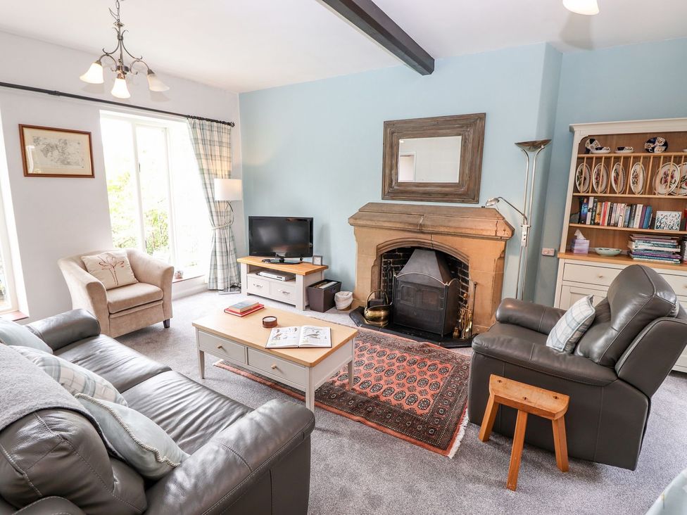 A living room with a fireplace and television at School Cottage in Windermere