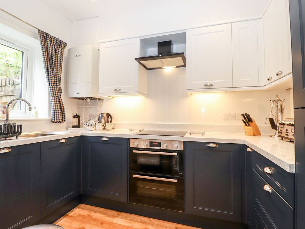 A kitchen with a sink, oven, and window at School Cottage in Windermere