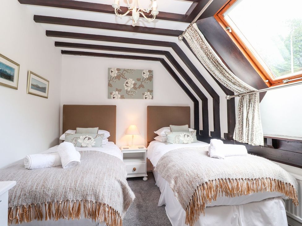 A bedroom with two beds and window at School Cottage in Windermere