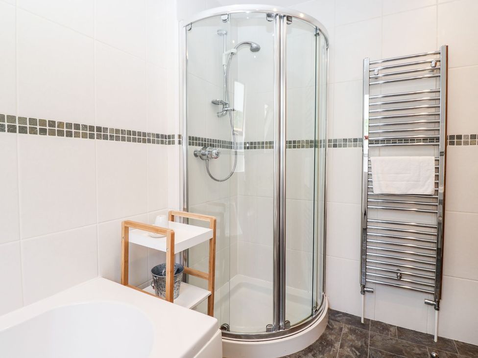 A bathroom with a shower and towel rack at School Cottage in Windermere