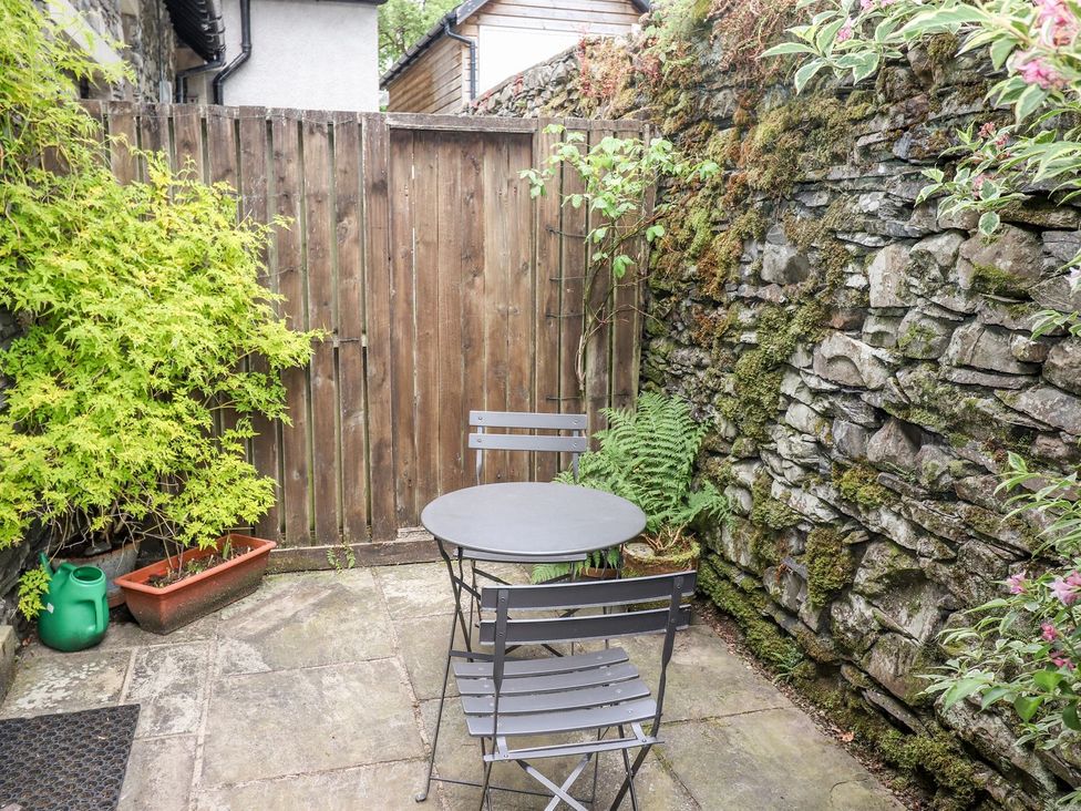 A garden with a table and chairs surrounded by plants at School Cottage in Windermere