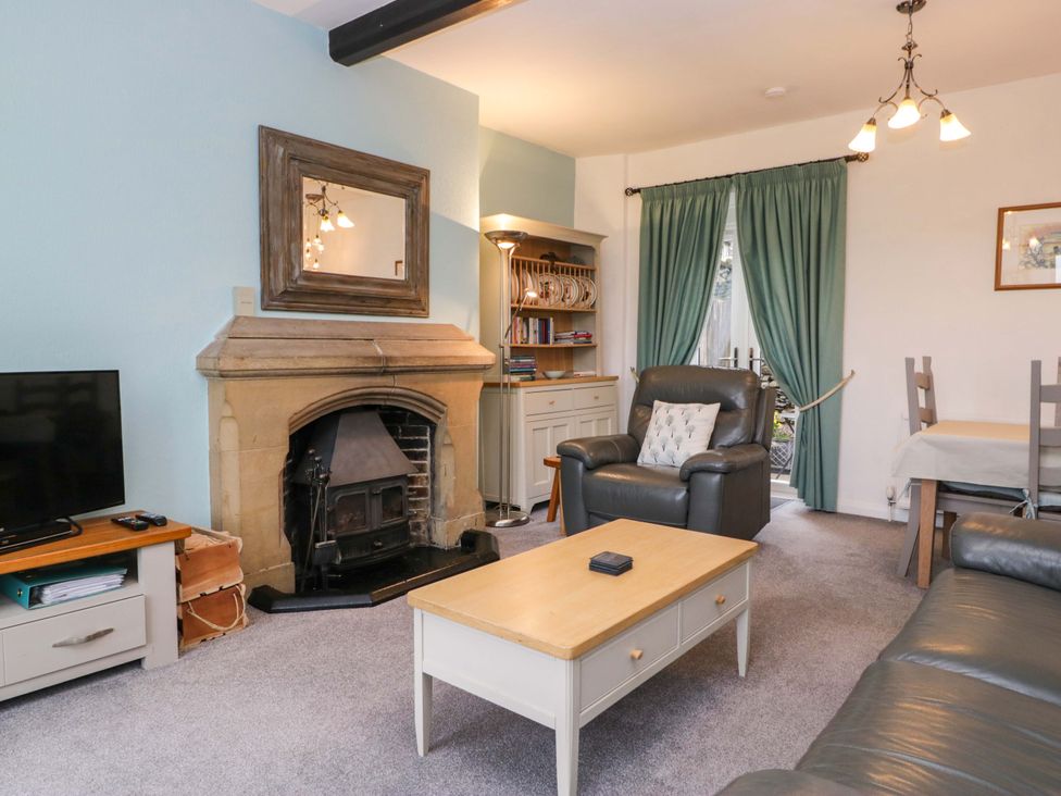 A living room with a fireplace and television at School Cottage in Troutbeck Bridge near Windermere