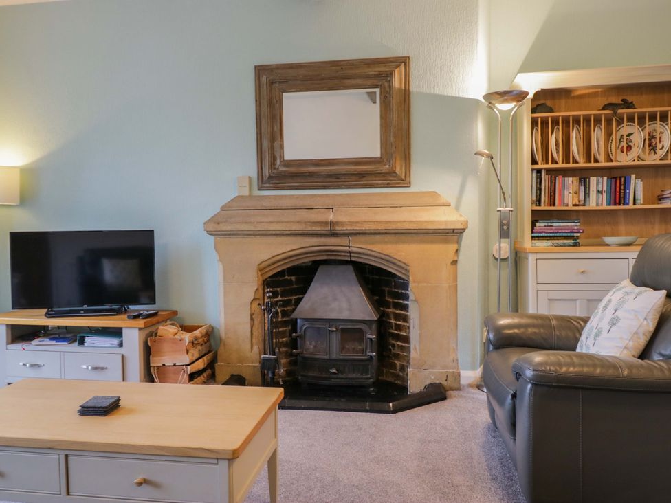 A living room with a television and fireplace at School Cottage, Troutbeck Bridge near Windermere