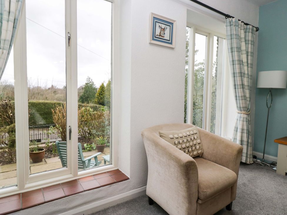 A living room with a large window and an armchair at School Cottage Troutbeck Bridge near Windermere