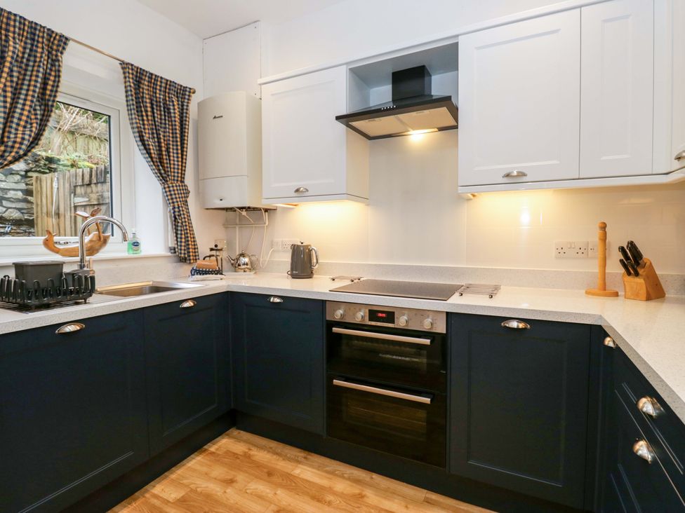 A kitchen with dark blue cabinets and appliances at School Cottage near Troutbeck Bridge