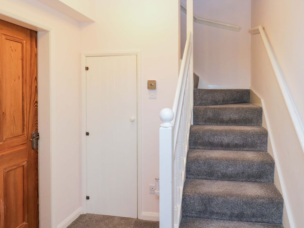 A hallway with a staircase and doors at School Cottage in Troutbeck Bridge near Windermere