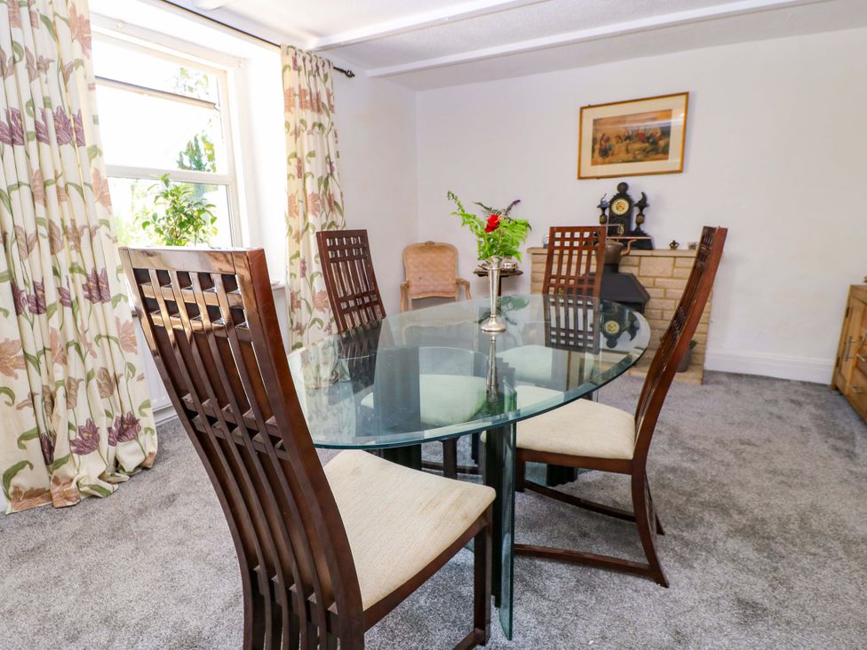 A dining room with a glass table and wooden chairs at The White House in Piddletrenthide