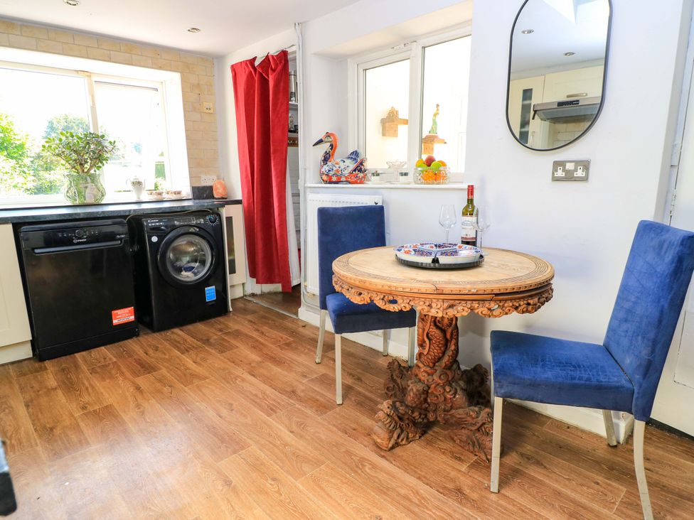 A kitchen with a dining area featuring a wooden table and blue chairs at The White House in Piddletrenthide