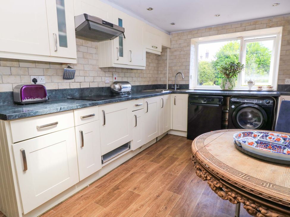 A kitchen with cabinets, sink, appliances, and a window at The White House in Piddletrenthide
