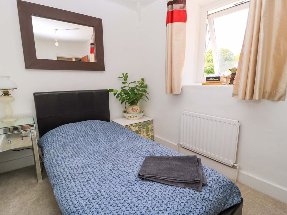 A bedroom with a bed, mirror, and plant at The White House in Piddletrenthide