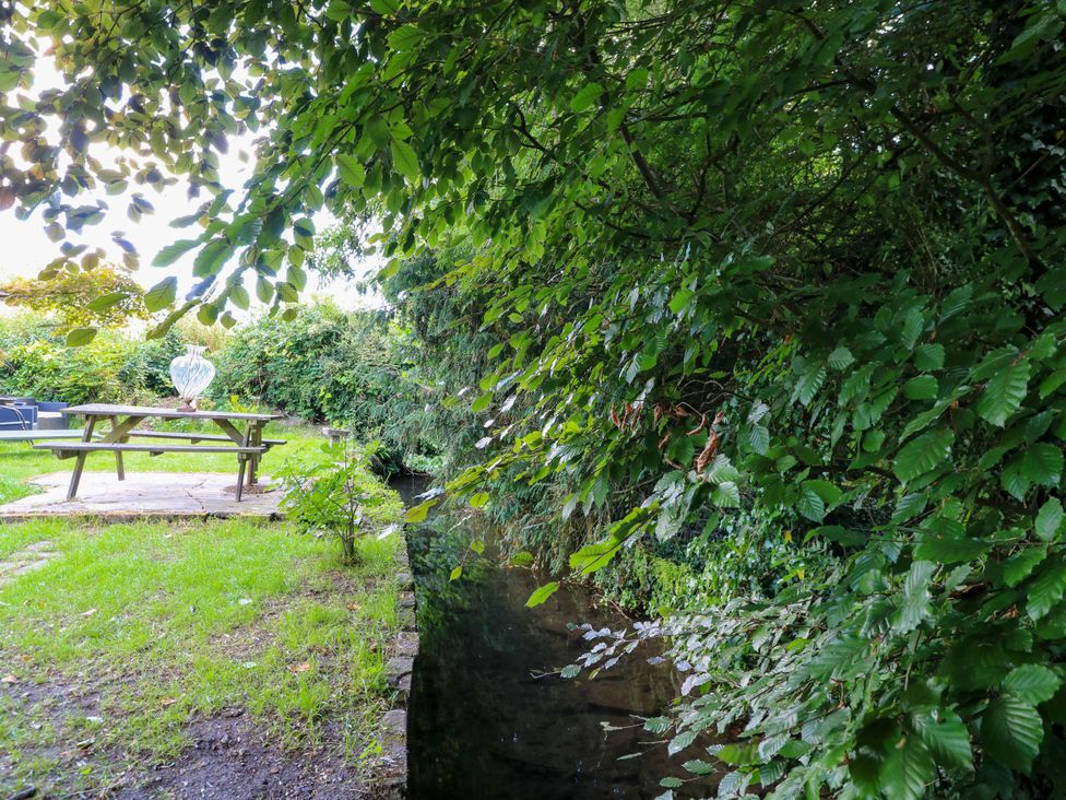 A picnic table and bench beside water in a garden at The White House in Piddletrenthide