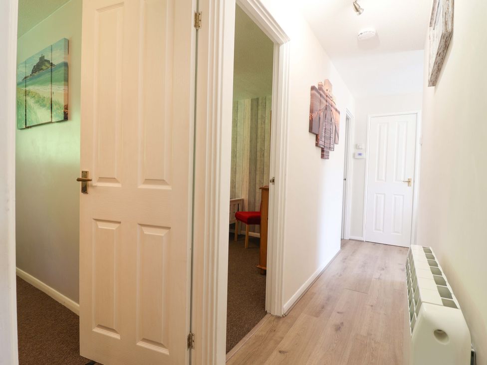 A hallway with doors and a table with a chair at Boo’s Bungalow Callington near Gunnislake