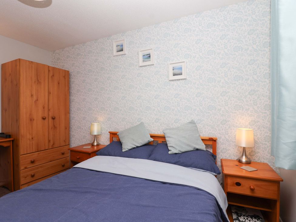A bedroom with a bed, bedside tables, a wardrobe and wall art at Boo’s Bungalow in Callington near Gunnislake