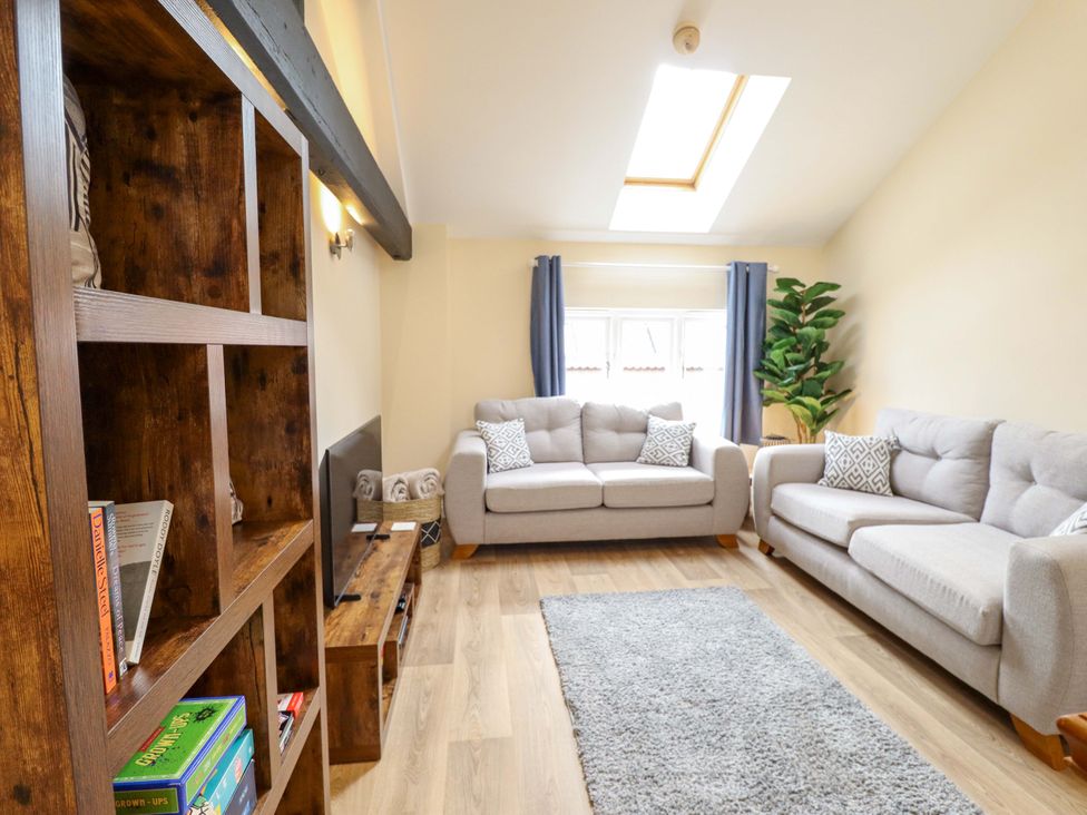 A living room with a bookshelf and sofas at 3 The Old Drill Hall in Alford