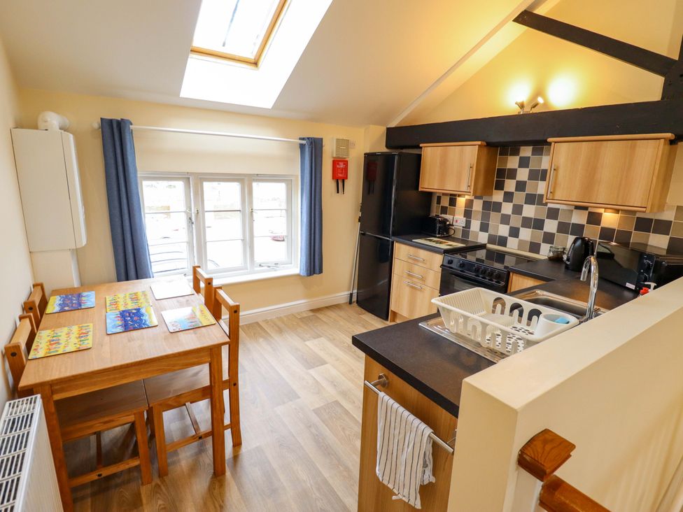 A kitchen with a dining table and appliances at 3 The Old Drill Hall in Alford