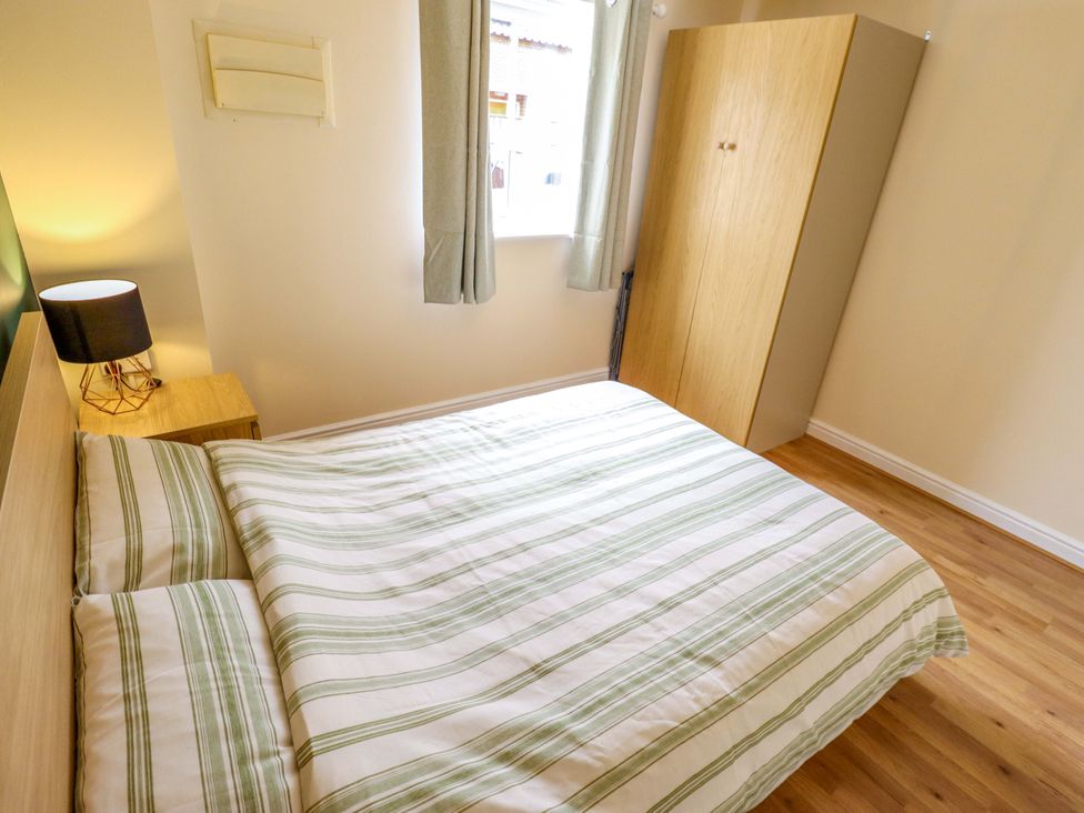 A bedroom with a bed, nightstand, lamp, window, and wardrobe at 3 The Old Drill Hall Alford