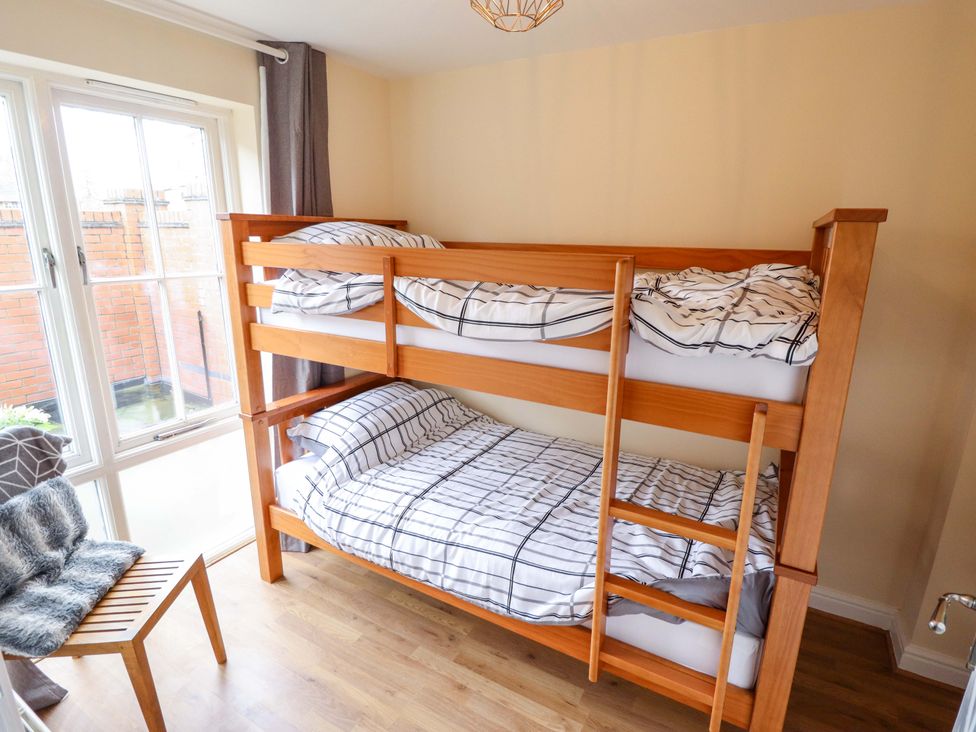 A bedroom with a bunk bed and a chair at 3 The Old Drill Hall Alford