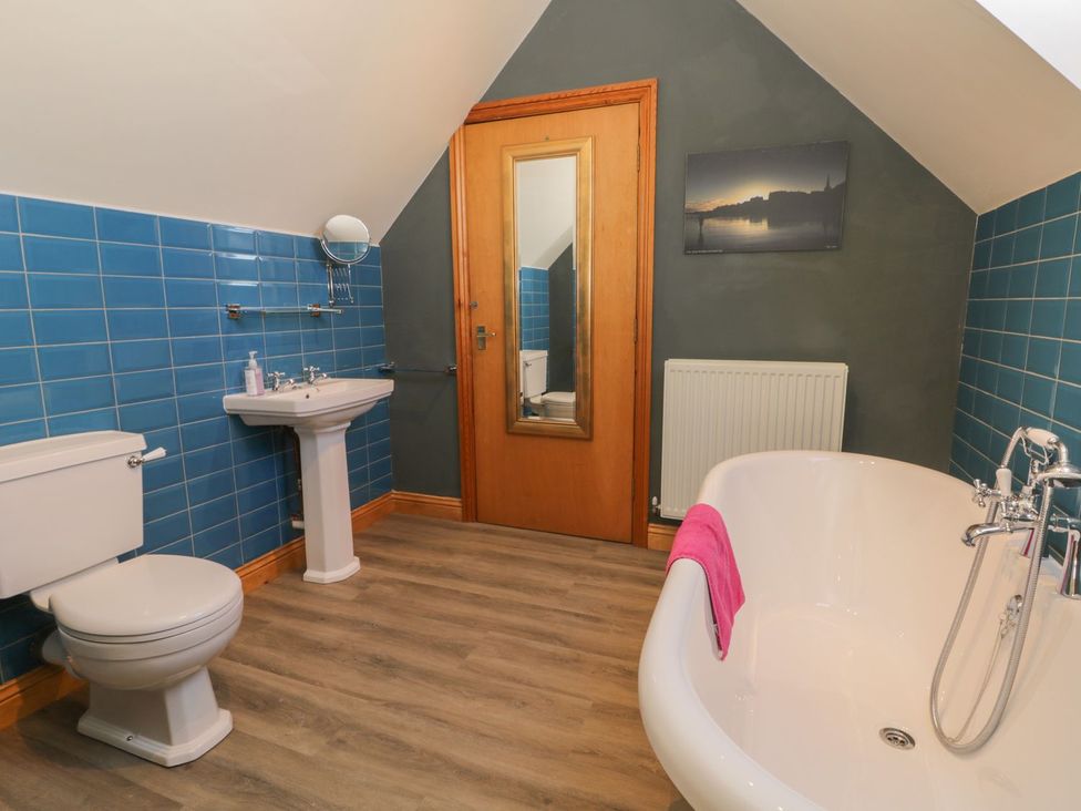 A bathroom with a bathtub, toilet, sink, and mirror at Atelier in Bridlington