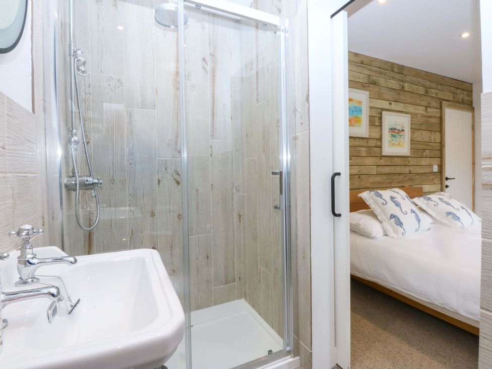 A bathroom with a shower and sink leading to a bedroom at Gowan Brae in Criccieth