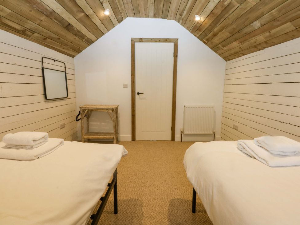A bedroom with two beds and a wooden table at Gowan Brae in Criccieth