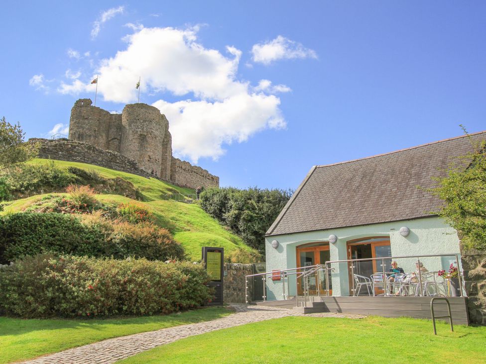 An outdoor area with a house and a castle in the background at Gowan Brae in Criccieth