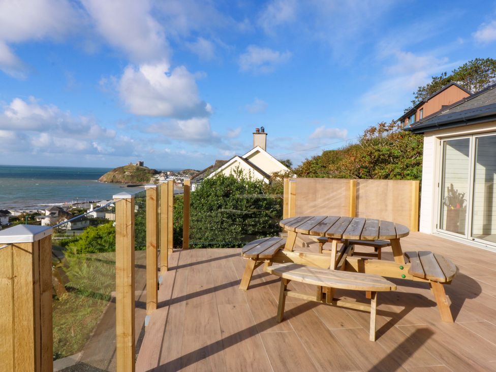 An outdoor space with a table and benches overlooking the sea at Gowan Brae in Criccieth