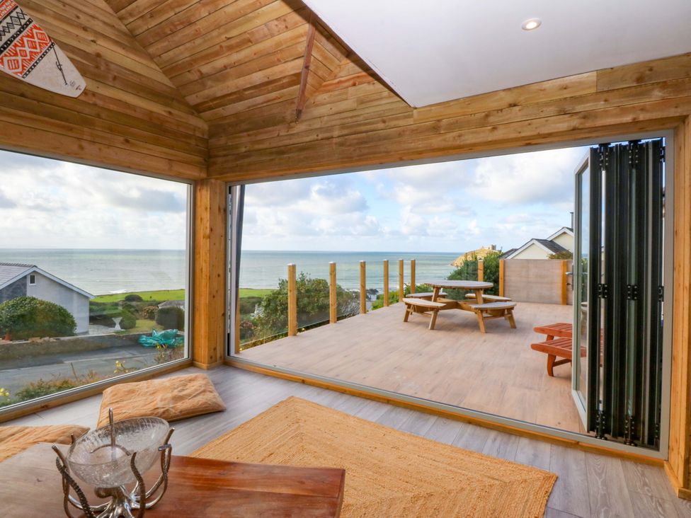 A living room with a view of the ocean and wooden deck at Gowan Brae in Criccieth