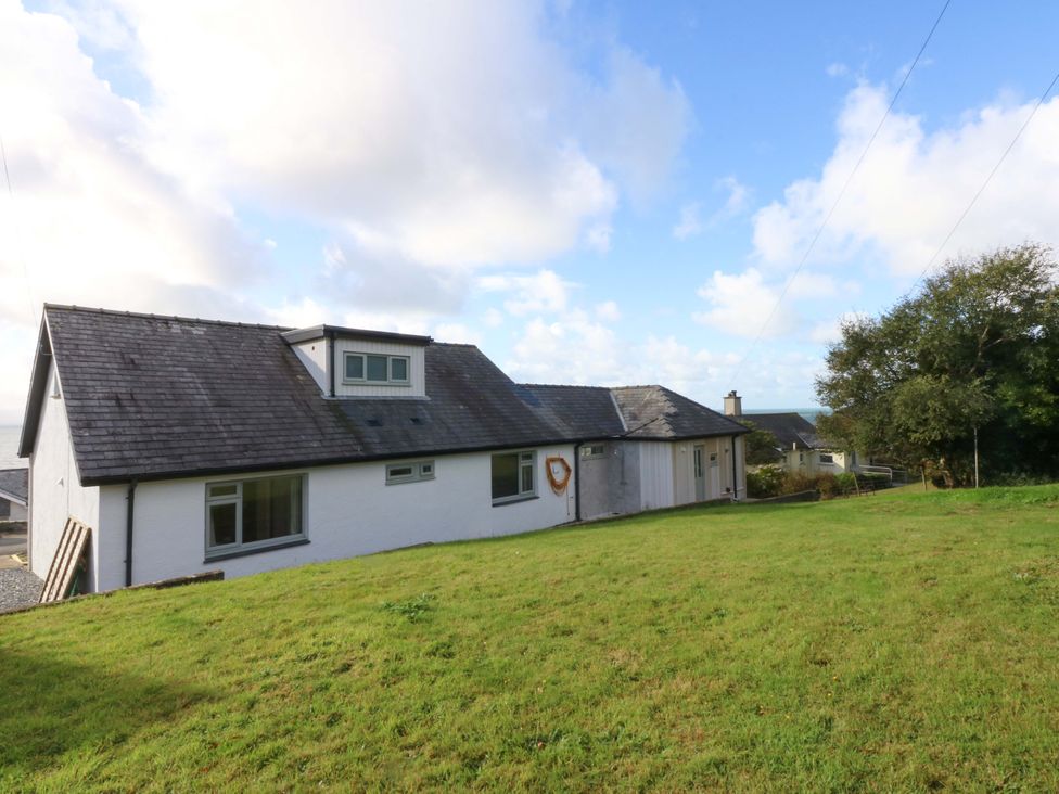 A house with a lawn and trees at Gowan Brae in Criccieth