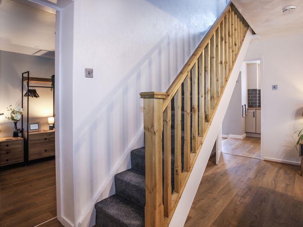 A hallway with a staircase and a door leading to a kitchen at Penrhos Walks in Holyhead