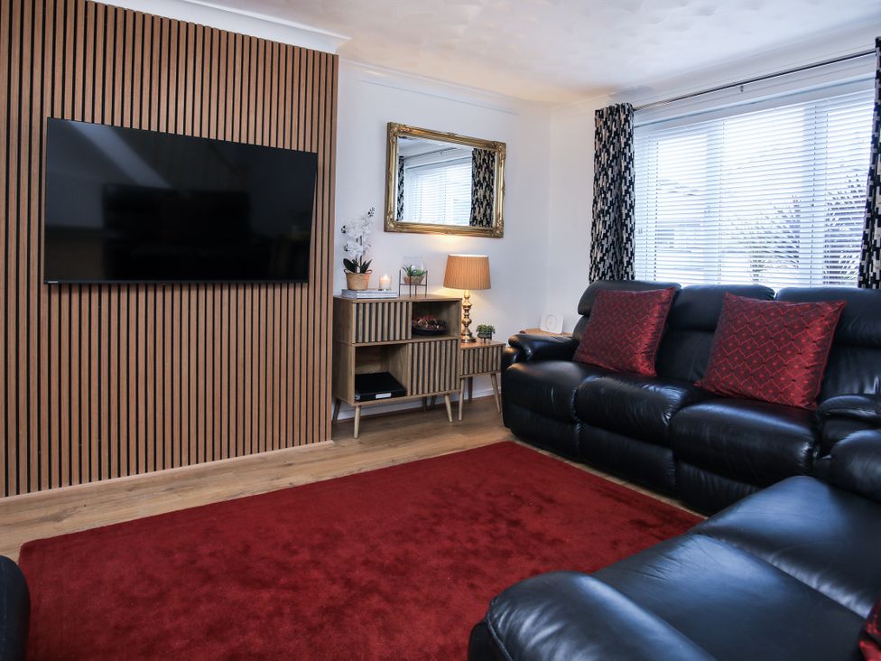 A living room with a television, sofa and mirror at Penrhos Walks in Holyhead