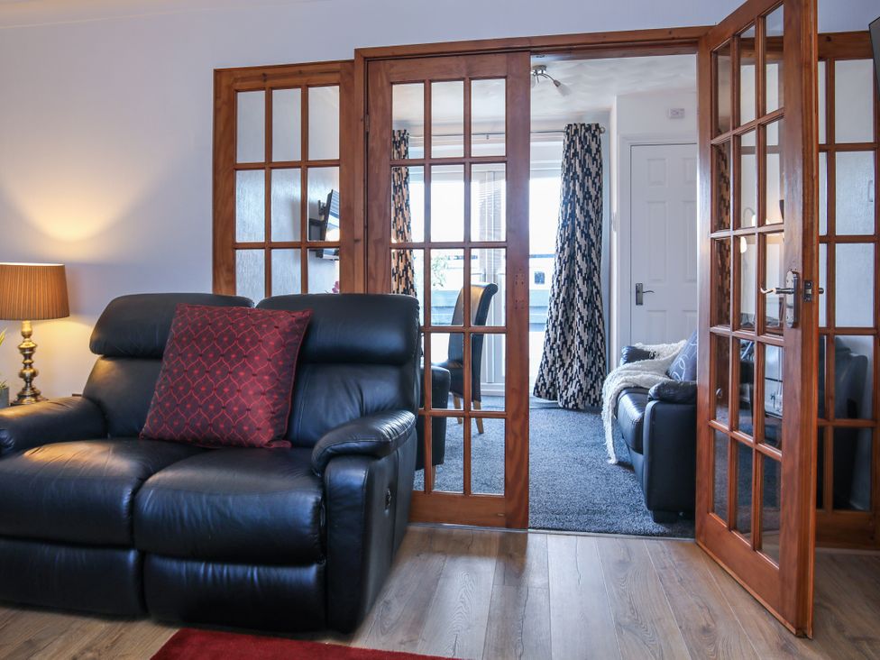 A living room with a sofa and doors at Penrhos Walks in Holyhead