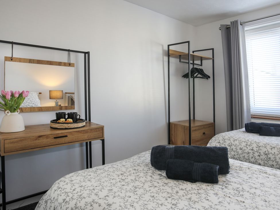 A bedroom with two beds and a dressing table at Penrhos Walks in Holyhead